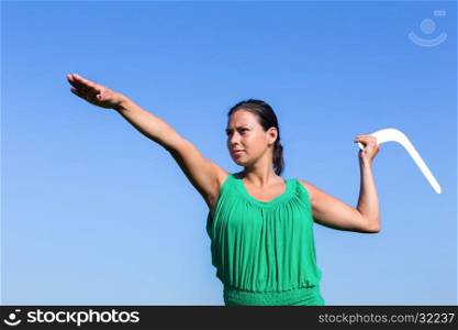 european woman throwing white boomerang in blue sky