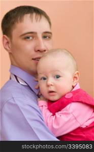 european young man and his baby daughter in his arms look into camera