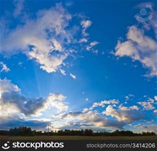 Evening blue sky panorama with clouds over plain and camp on forest Four shots stitch image.