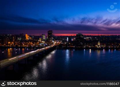 evening city aerial view with the multicolored city lights and bridge across the river. Dnipro, Ukraine