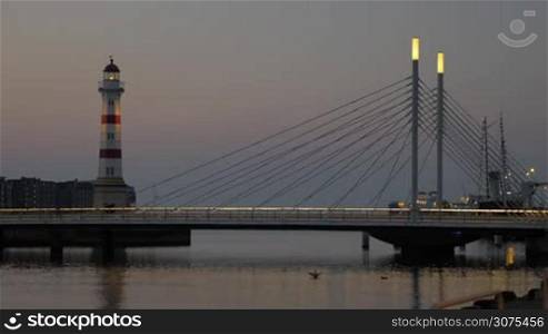 Evening cityscape with lit lighthouse and bridge over the river near the dockyard. Malmo, Sweden