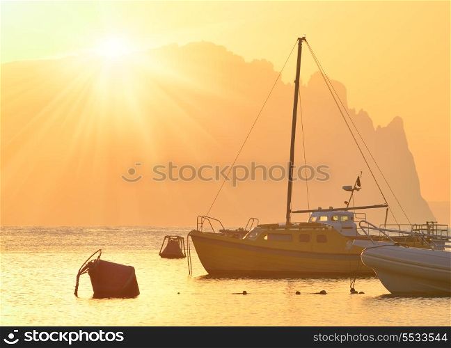 Evening in a bay with ships at sunset against mountains
