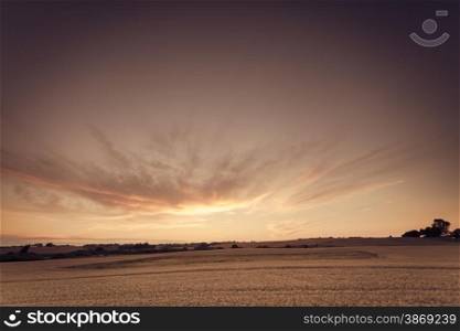 Evening landscape. Beautiful sunset or sunrise over summer field meadow with dramatic sky, Image in vintage retro style