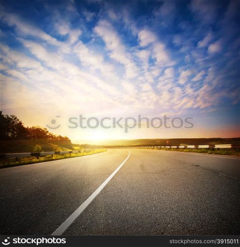 Evening landscape with a road going into the horizon at sunset sky