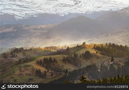 Evening light in spring carpathian mountains. Snow and green fields