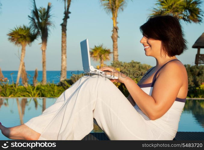 evening light picture of woman with laptop computer at tropical resort