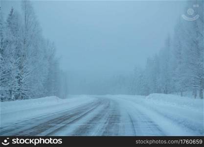 Evening northern forest. Empty highway. Lots of snow and fog. Empty Winter Highway in the Forest