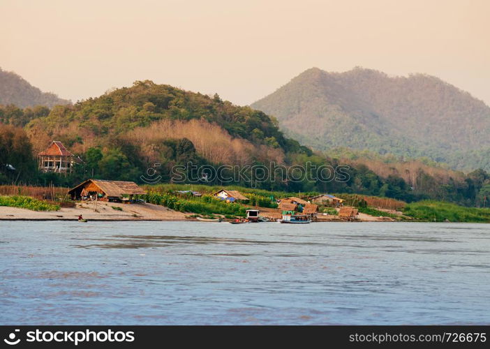 Evening rural village scene and peaceful Mae Khong river with mountain forest in Luang Prabang - Laos