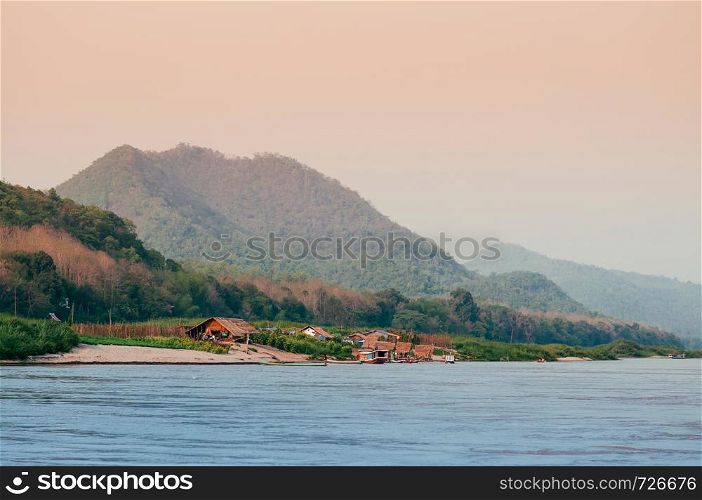 Evening rural village scene and peaceful Mae Khong river with mountain forest in Luang Prabang - Laos