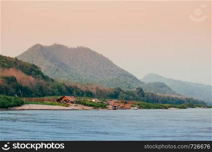 Evening rural village scene and peaceful Mae Khong river with mountain forest in Luang Prabang - Laos