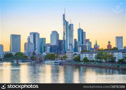 Evening scene with touristic boats on river by city embankment, modern architecture skyline against afterglow sky, Frankfurt am Main, Germany
