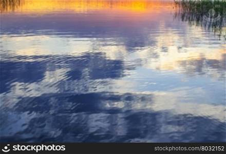 Evening sky reflection in lake with reeds abstract background. Lake Vanern, Varmland, Sweden.