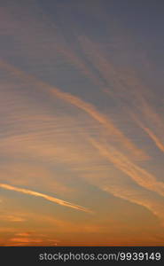 evening sky with red cirrus clouds with airplane trails