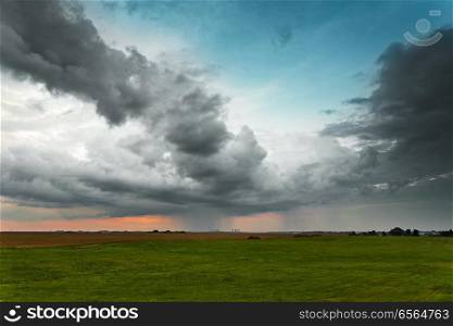 Evening storm. Dramatic clouds and sky over green fields and power plant