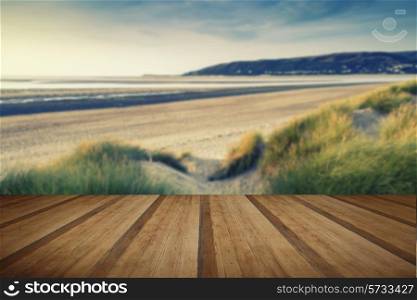 Evening Summer landscape over grassy sand dunes on beach with Instagram effect filter with wooden planks floor