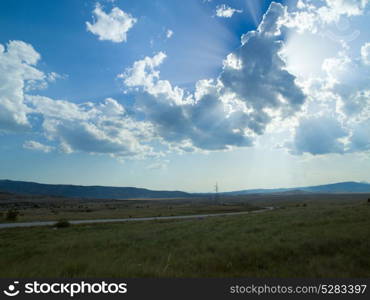 Evening summer landscape with green grass, road and clouds