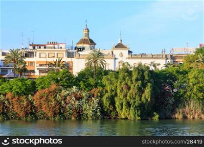 Evening summer Seville city view with Guadalquivir river and blossoming riverside (Spain).