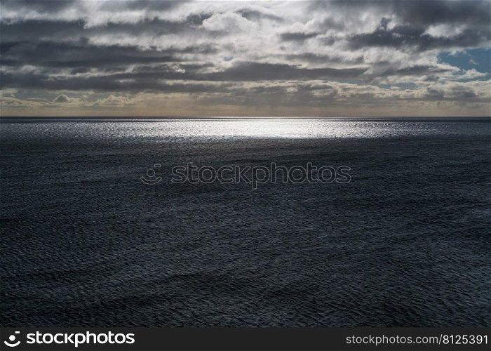 Evening sun glare over the waters of the Atlantic Ocean Seascape with glowing solar glare on the sea surface and sunset sky.