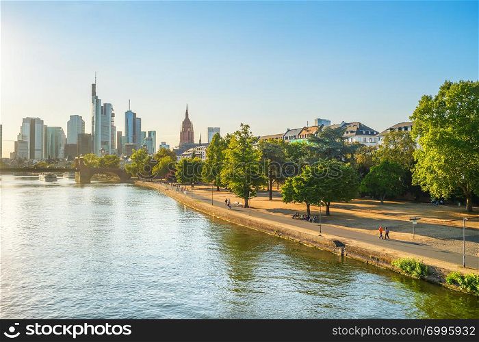 Evening sunshine over Main river embankment, modern city skyline in background, Frankfurt am Main, Germany