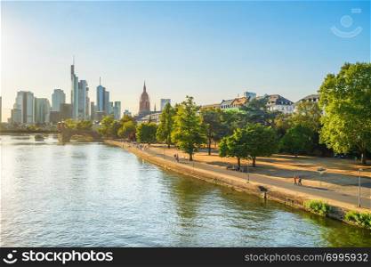 Evening sunshine over Main river embankment, modern city skyline in background, Frankfurt am Main, Germany