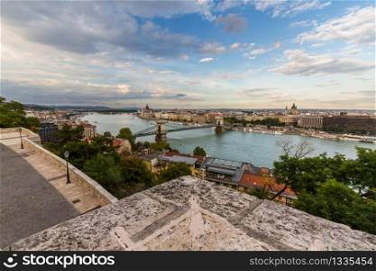 Evening view of river danube, chain bridge and Hungarian Parliament Building, Budapest, Hungary, landscape, clouds in sky, wide angle, parapet in foreground.