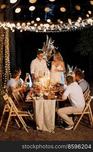 evening wedding family dinner in the forest with light bulbs and candles