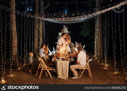 evening wedding family dinner in the forest with light bulbs and candles