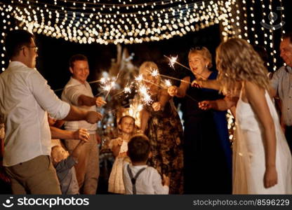 evening wedding family dinner in the forest with light bulbs and candles