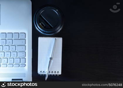 Evening work place and laptop. Modern laptop on evening work place, coffee cup and notebook with pen, view from above