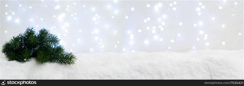 Evergreen fir tree in snow with glowing lights in background. Happy Christas and holidays concept, web banner. White christmas with snow