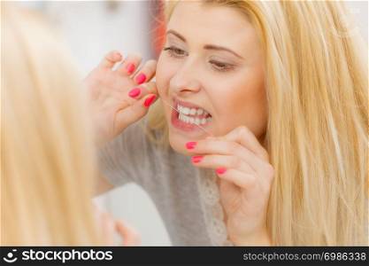 Everyday oral hygiene, dentistry concept. Woman cleaning her teeth using dental floss. Woman cleaning her teeth using dental floss