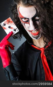 Evil clown with cards in dark room