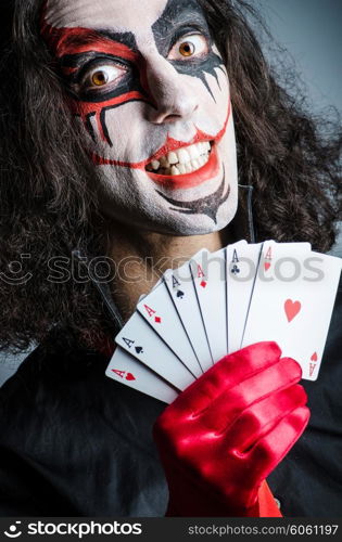 Evil clown with cards in dark room