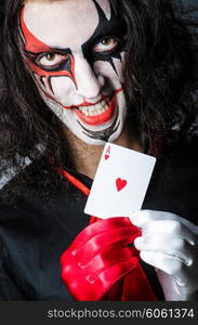 Evil clown with cards in dark room