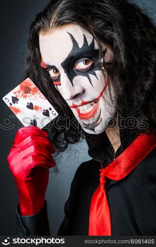 Evil clown with cards in dark room