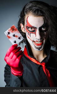 Evil clown with cards in dark room