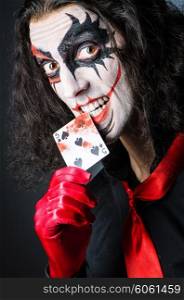 Evil clown with cards in dark room