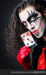 Evil clown with cards in dark room