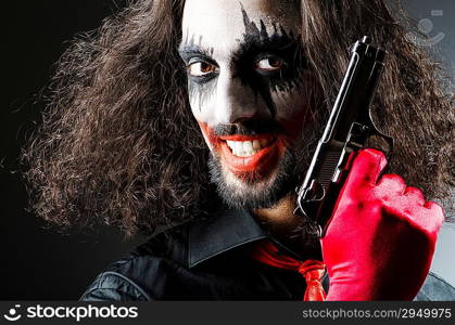 Evil clown with gun in dark room