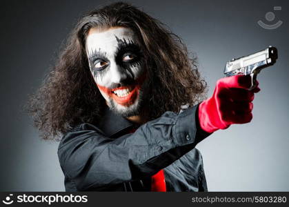 Evil clown with gun in dark room