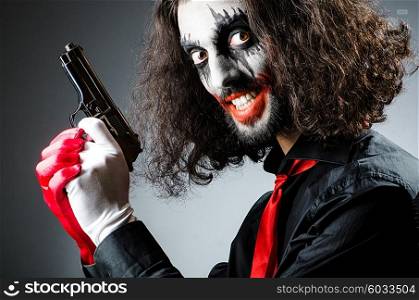Evil clown with gun in dark room