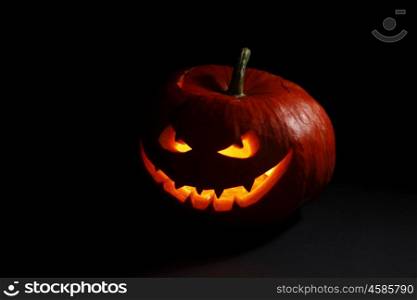 Evil smiling glowing halloween pumpkin on dark background
