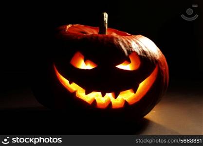 Evil smiling glowing halloween pumpkin on dark background