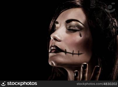 Evil witch on black background, closeup portrait of young beautiful girl with terrifying makeup, closed eyes, Halloween party concept