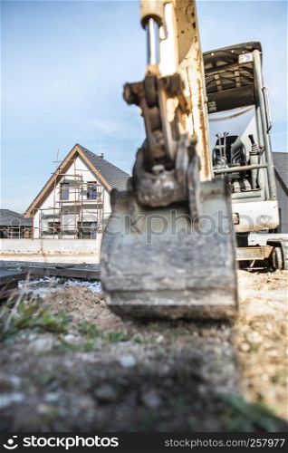 Excavator and newly built houses on construction site