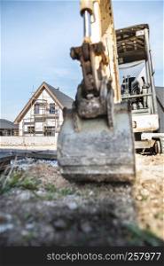 Excavator and newly built houses on construction site