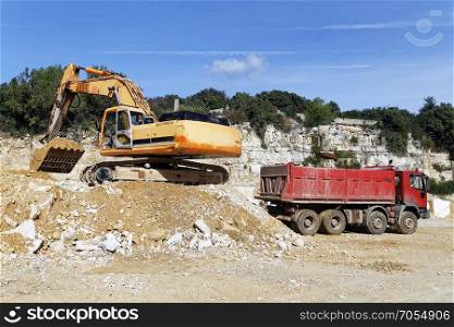 Excavator loading sand into dump truck