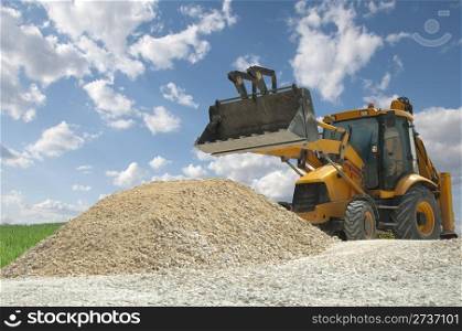 Excavator to a pile of rubble on blue sky