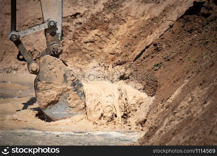 Excavator working with soil and water, during earthmoving works