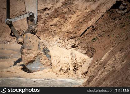 Excavator working with soil and water, during earthmoving works